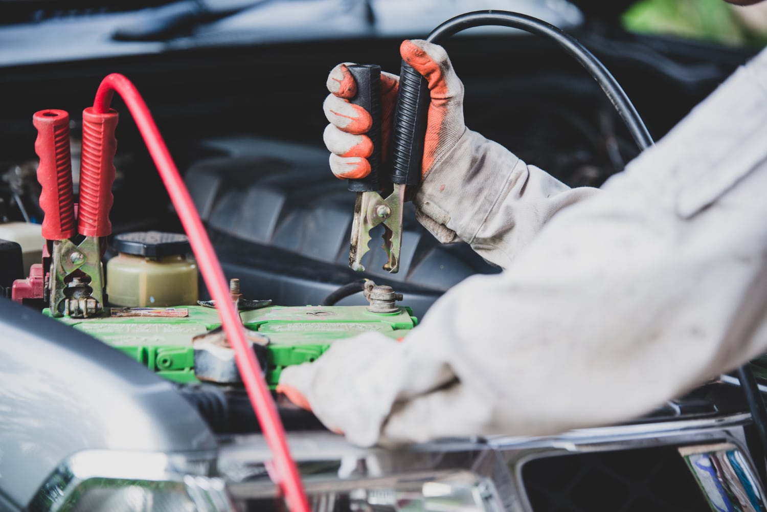 Towing technician using booster cables to jump-start a vehicle, representing car boosting services in Edmonton.
